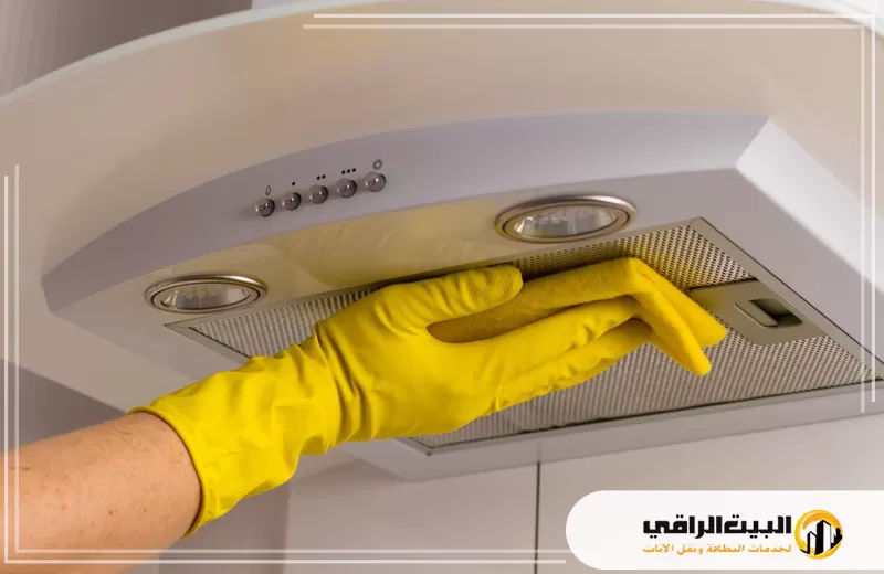 تنظيف ارضيات وجدران المطابخ بالرياض 0550071994 البيت الراقي شخص يرتدي قفازات صفراء يقوم بتنظيف شفاط المطبخ في مطبخ حديث