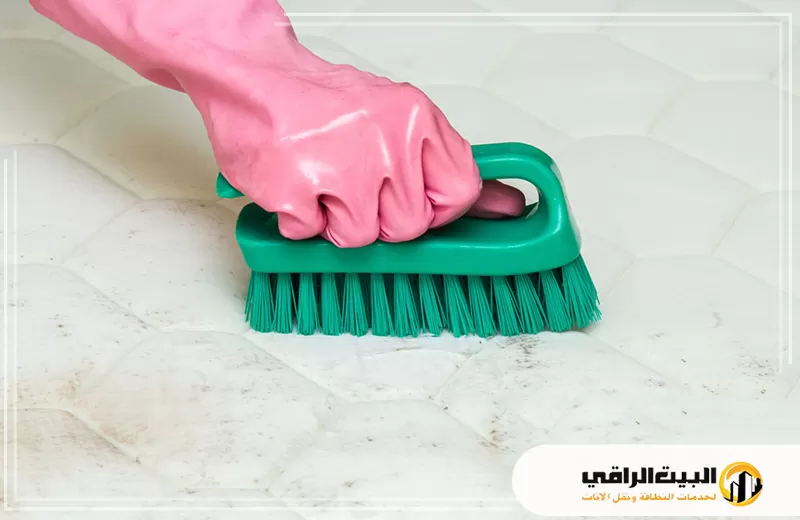 تنظيف مراتب سرير بالرياض 0550071994 البيت الراقي شخص يرتدي قفازات وردية يقوم بتنظيف مرتبة سرير.