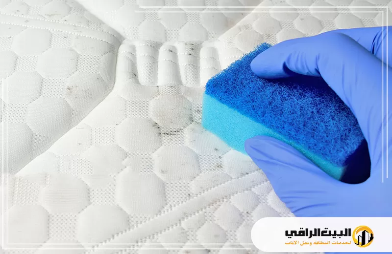 تنظيف مرتبة السرير من البقع الصعبة بالرياض 0550071994 البيت الراقي شخص يرتدي قفازات زرقاء يقوم بتنظيف مرتبة سرير في الرياض