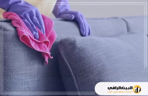تنظيف كنب قماش قطني 0550071994 البيت الراقي تنظيف كنب قماش قطني يتطلب العناية والاهتمام من أجل الحفاظ على مظهره ونظافته. في الصورة، نرى أحد الفنيين يقوم بتنظيف الكنب باستخدام قطعة قماش ناعمة بينما يرتدي قفازات لحماية اليدين من المواد الكيميائية.