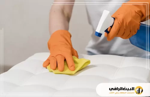 تنظيف بقع المناكير من الأقمشة 0550071994 البيت الراقي تنظيف بقع المناكير من الأقمشة يعد أمرًا ضروريًا للحفاظ على مظهر الأثاث. في هذه الصورة، يظهر شخص يرتدي قفازات واقية.